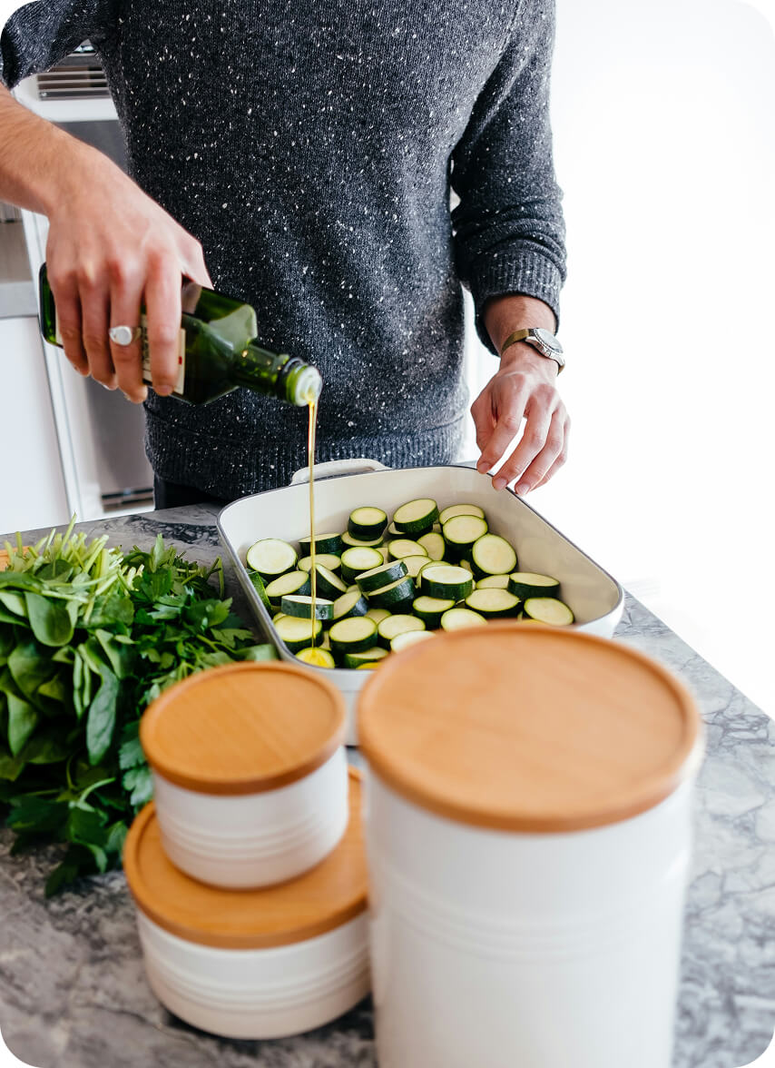 A person pouring oil onto vegetables.