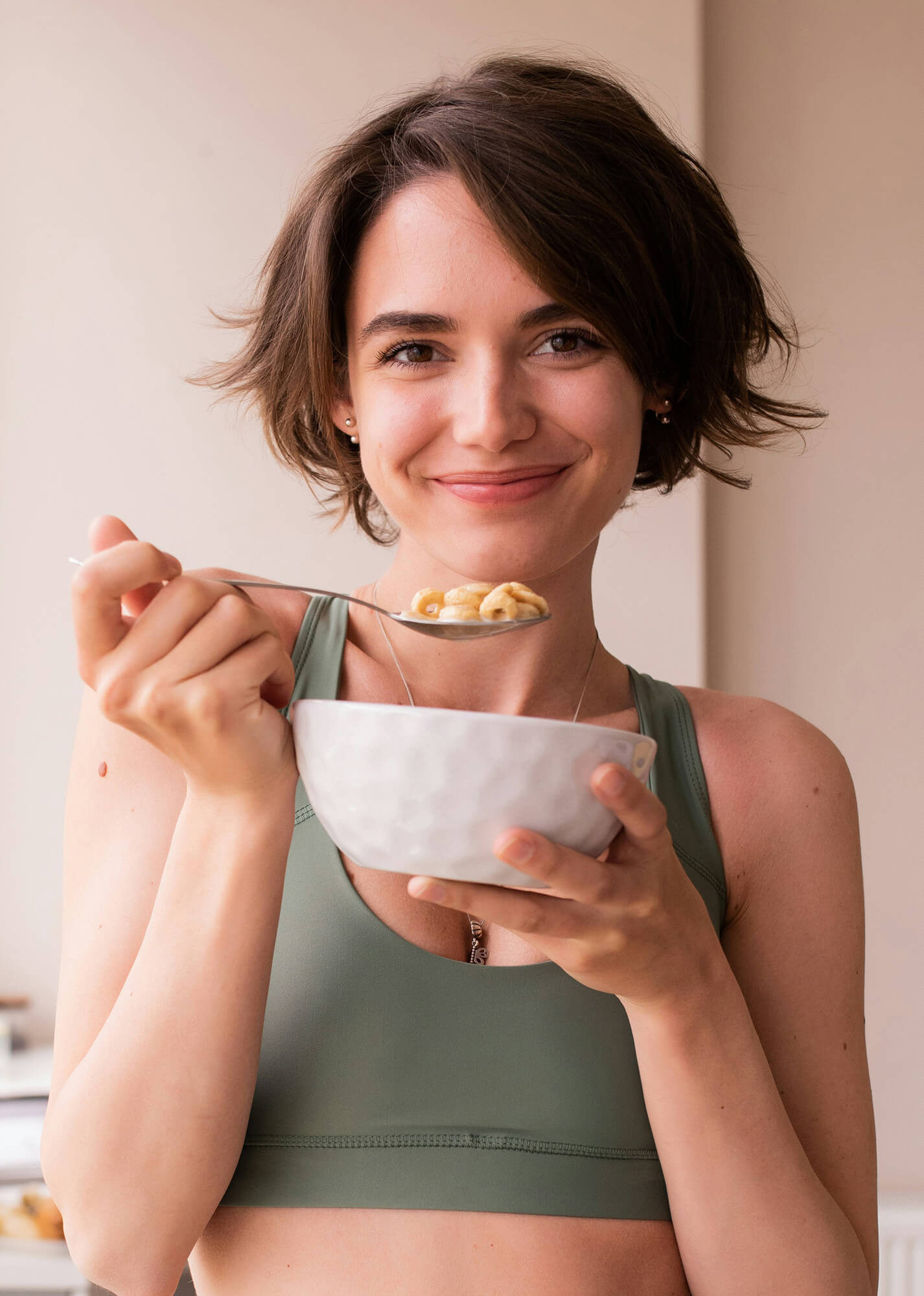 A person smiling and eating food from a bowl.