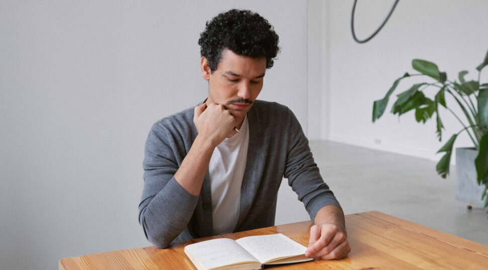 Man sitting at table reading a book