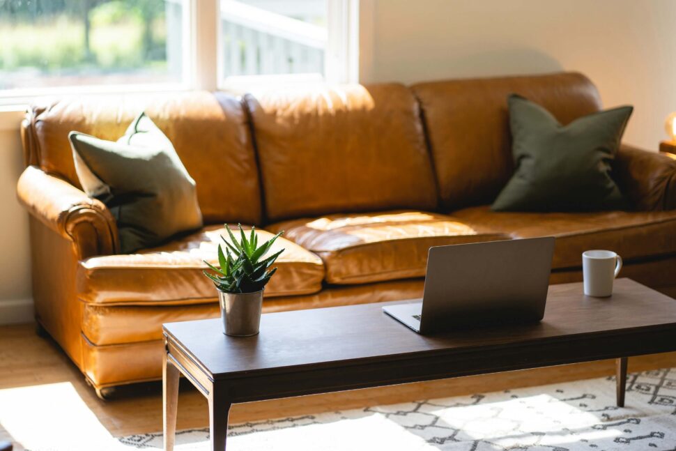 View of a brown sofa with a laptop on the coffee table