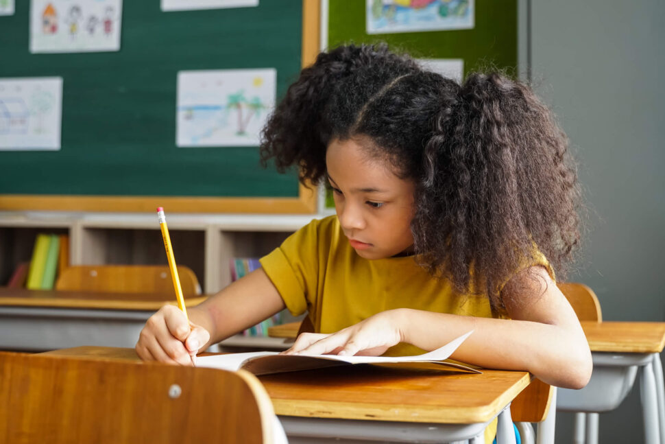 Young girl writing at her desk in a classroom