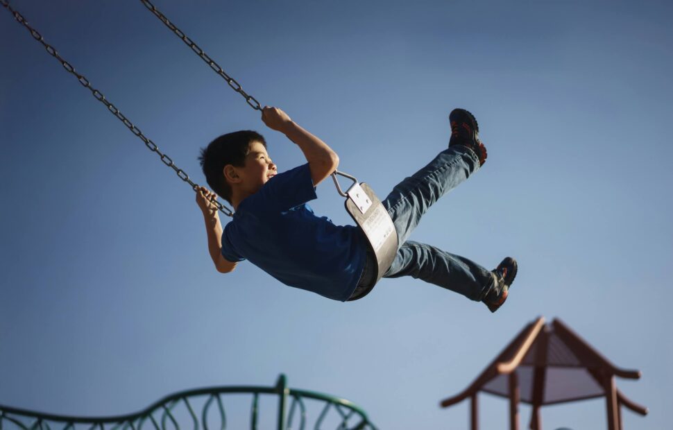 Young boy swinging on swing at a playground